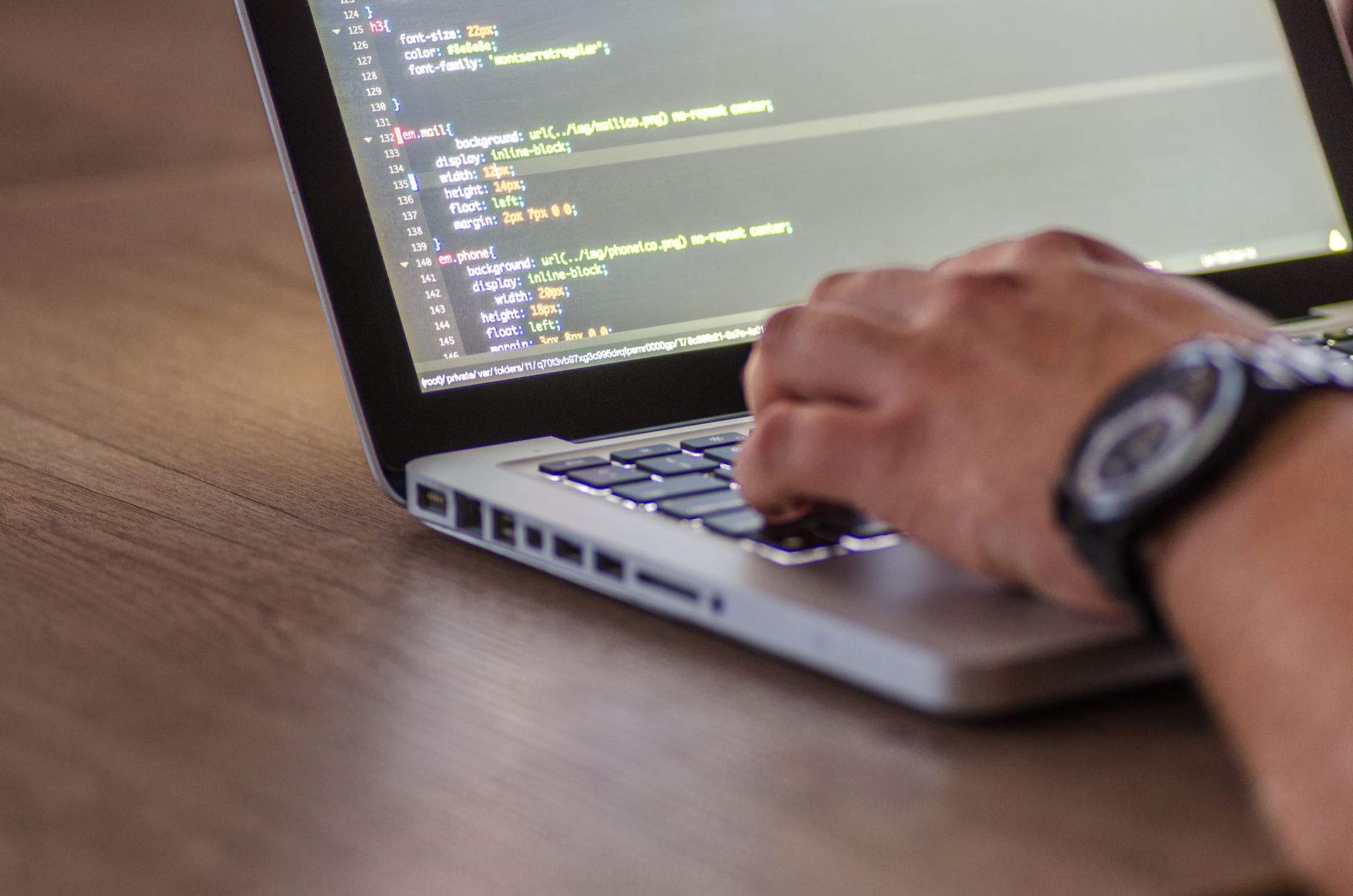 Pessoa digitando em notebook com código na tela