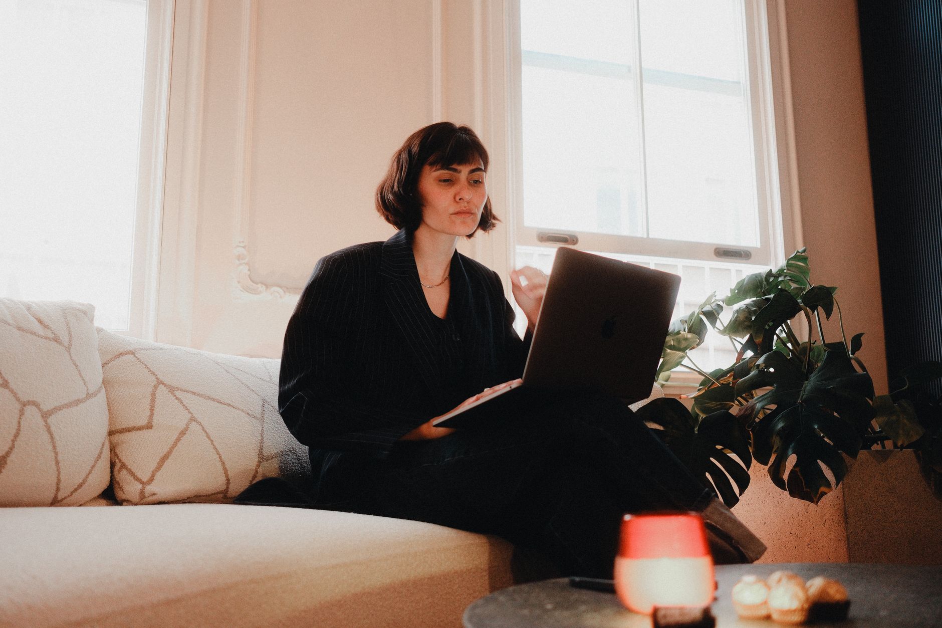 Profissional sentada em sofá usando notebook em ambiente de home office