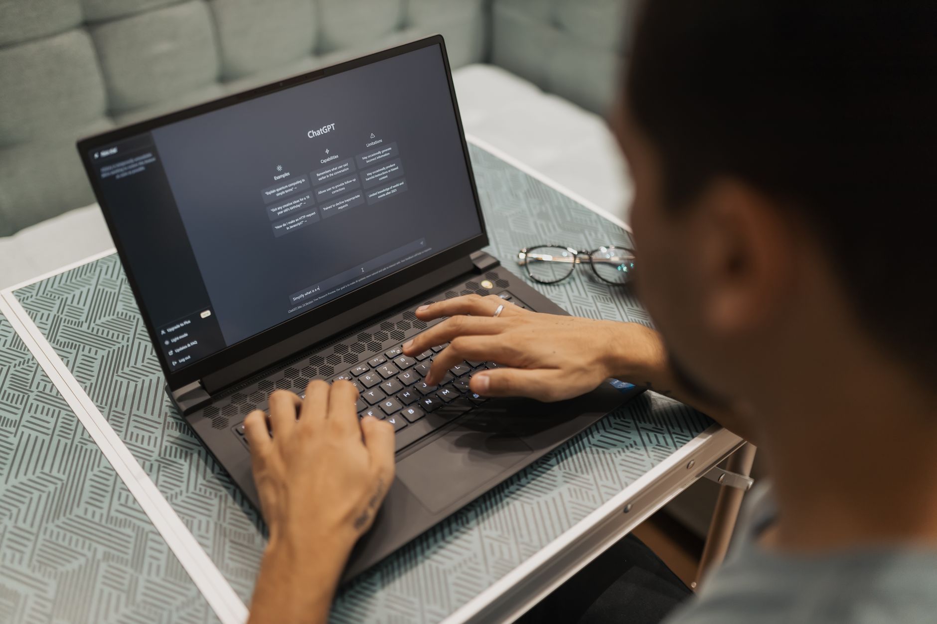 Pessoa digitando em notebook com a tela de um assistente de IA aberta