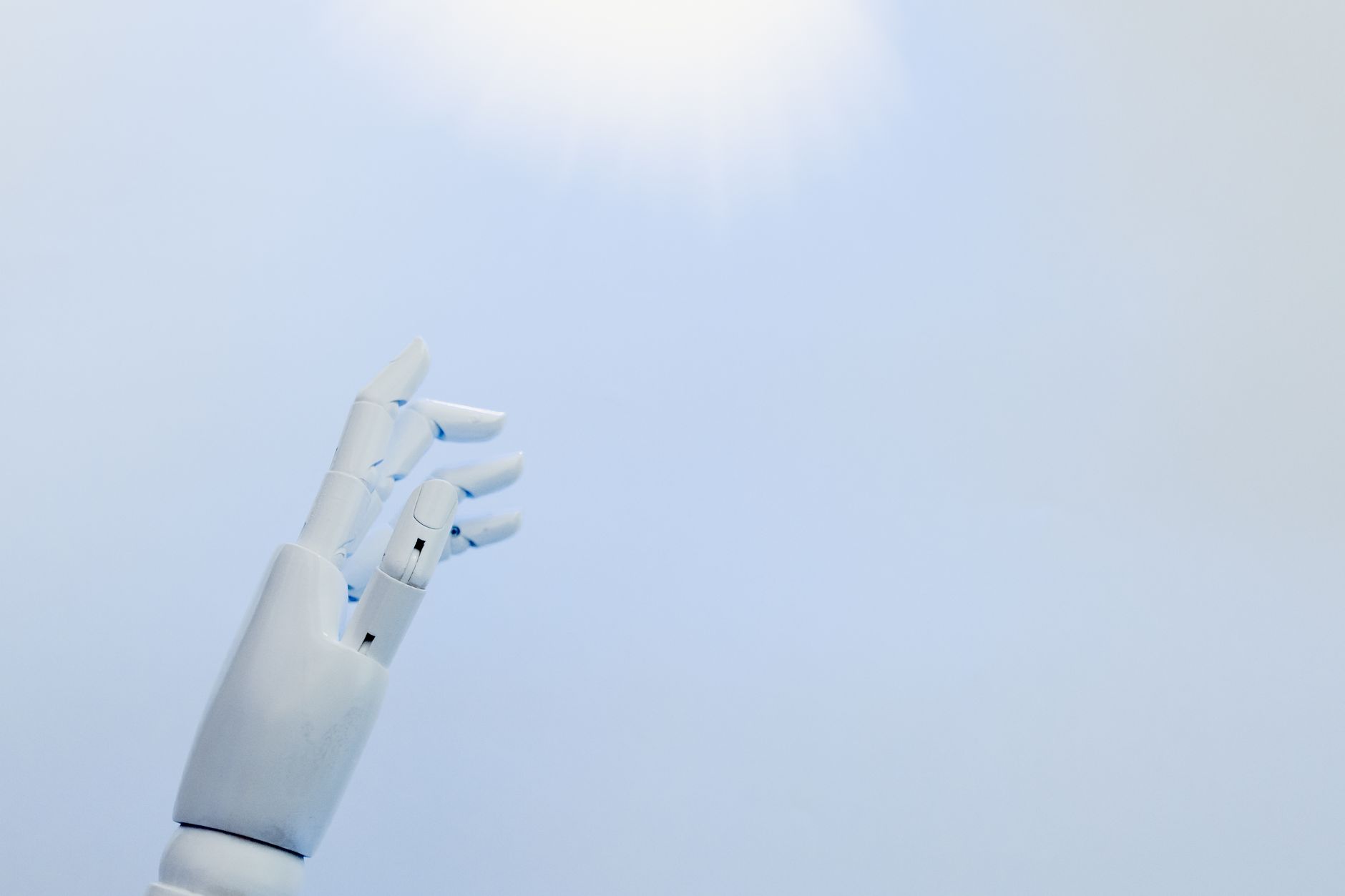 Braço robótico branco apontando para o céu azul representando avanço da inteligência artificial
