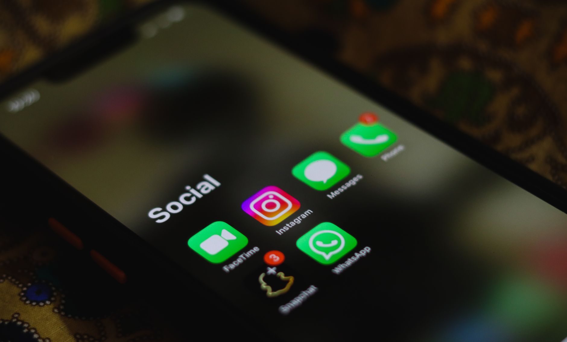 Tela de smartphone mostrando pasta "Social" com ícones do Instagram, WhatsApp, Mensagens e FaceTime
