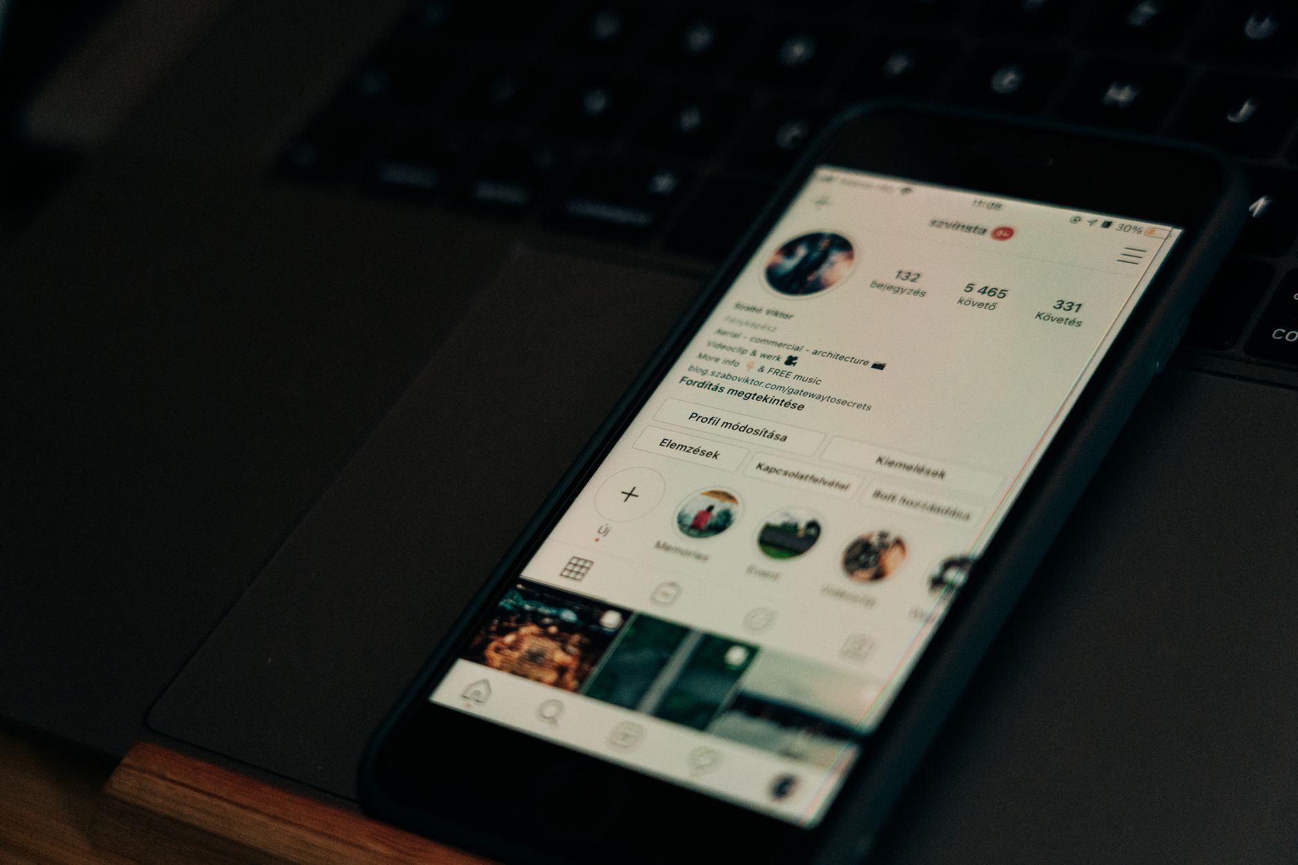 Smartphone sobre teclado de notebook mostrando perfil do Instagram com número de seguidores e publicações