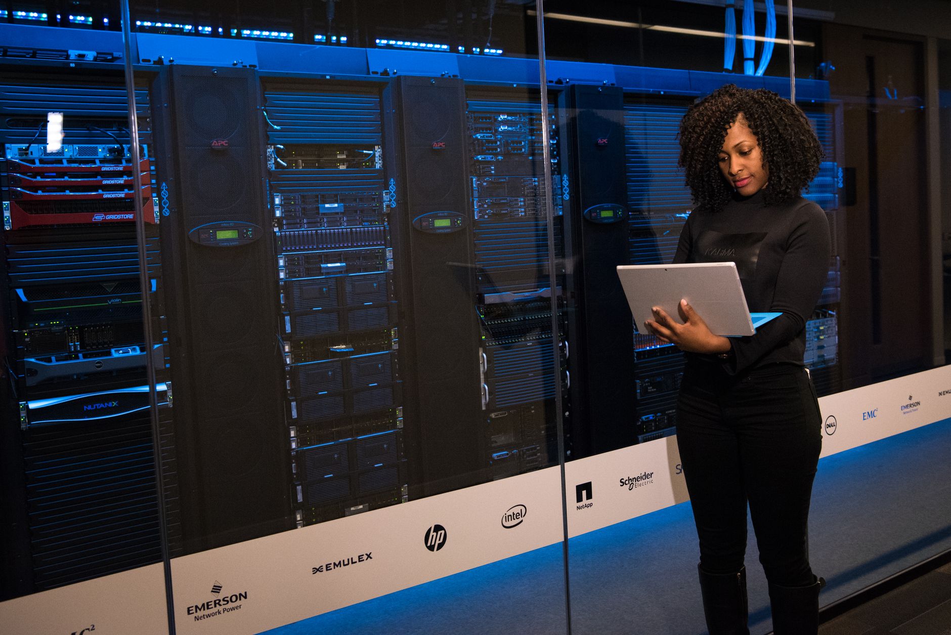 Profissional de TI analisando um tablet em frente a racks de servidores em um data center