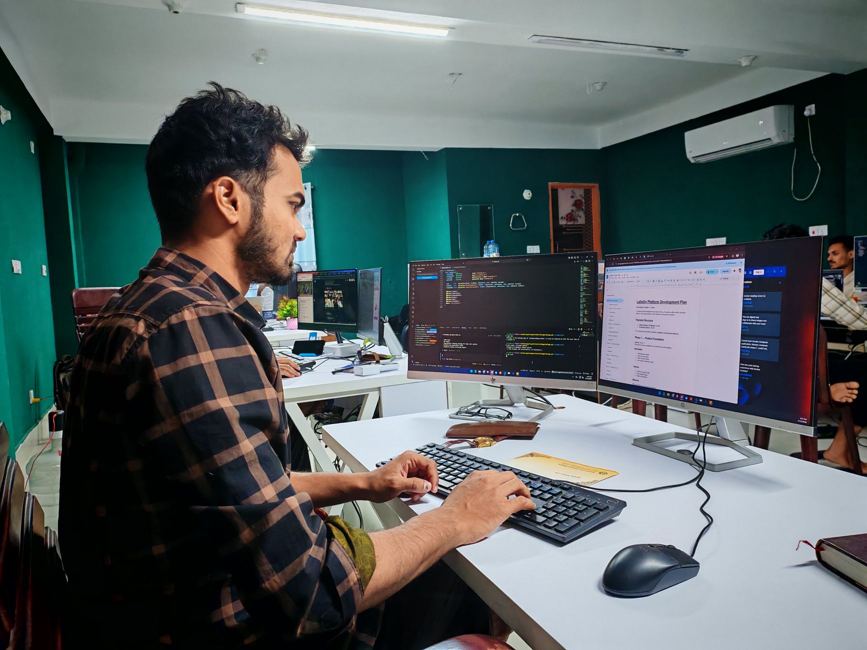 Desenvolvedor trabalhando em múltiplos monitores com código e documentos em um escritório